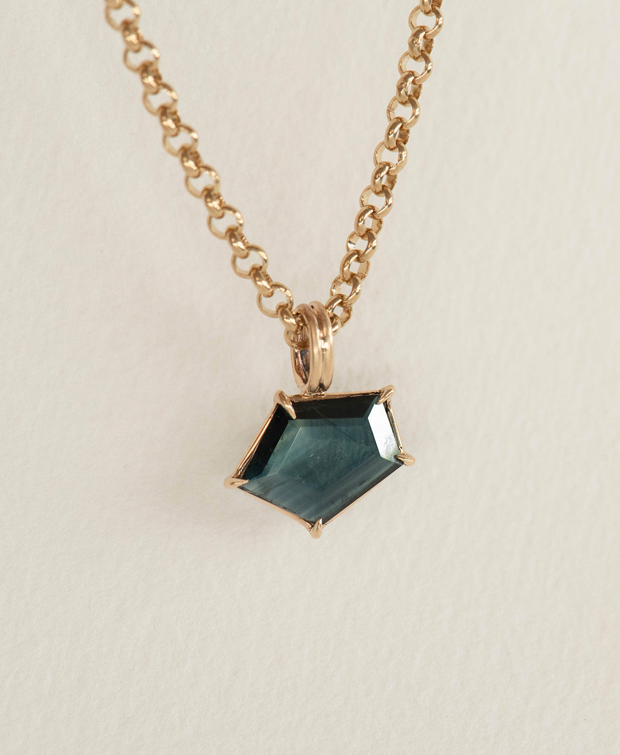 Close up of the One of a Kind Charm 497 with dark teal portrait cut Sapphire on a belcher chain.