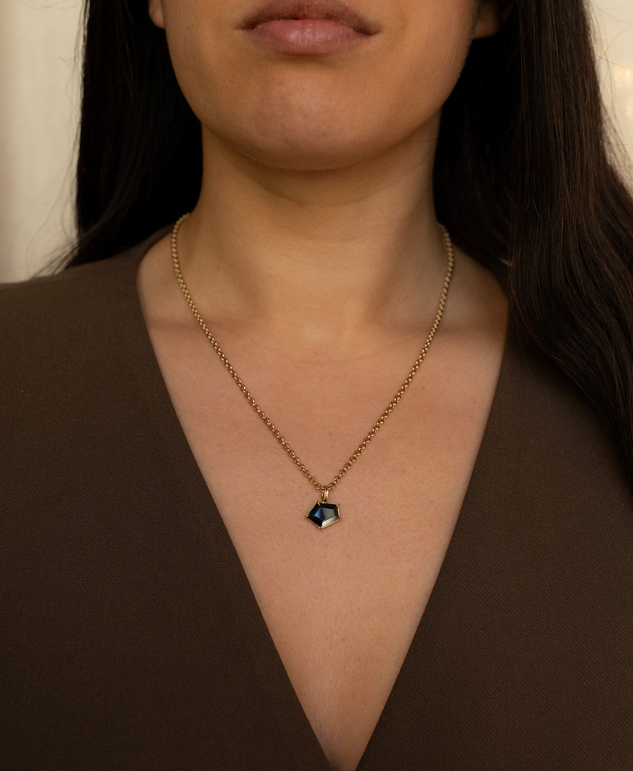 One of a Kind Charm 497 with a dark teal portrait cut Sapphire worn by a model on a belcher chain.