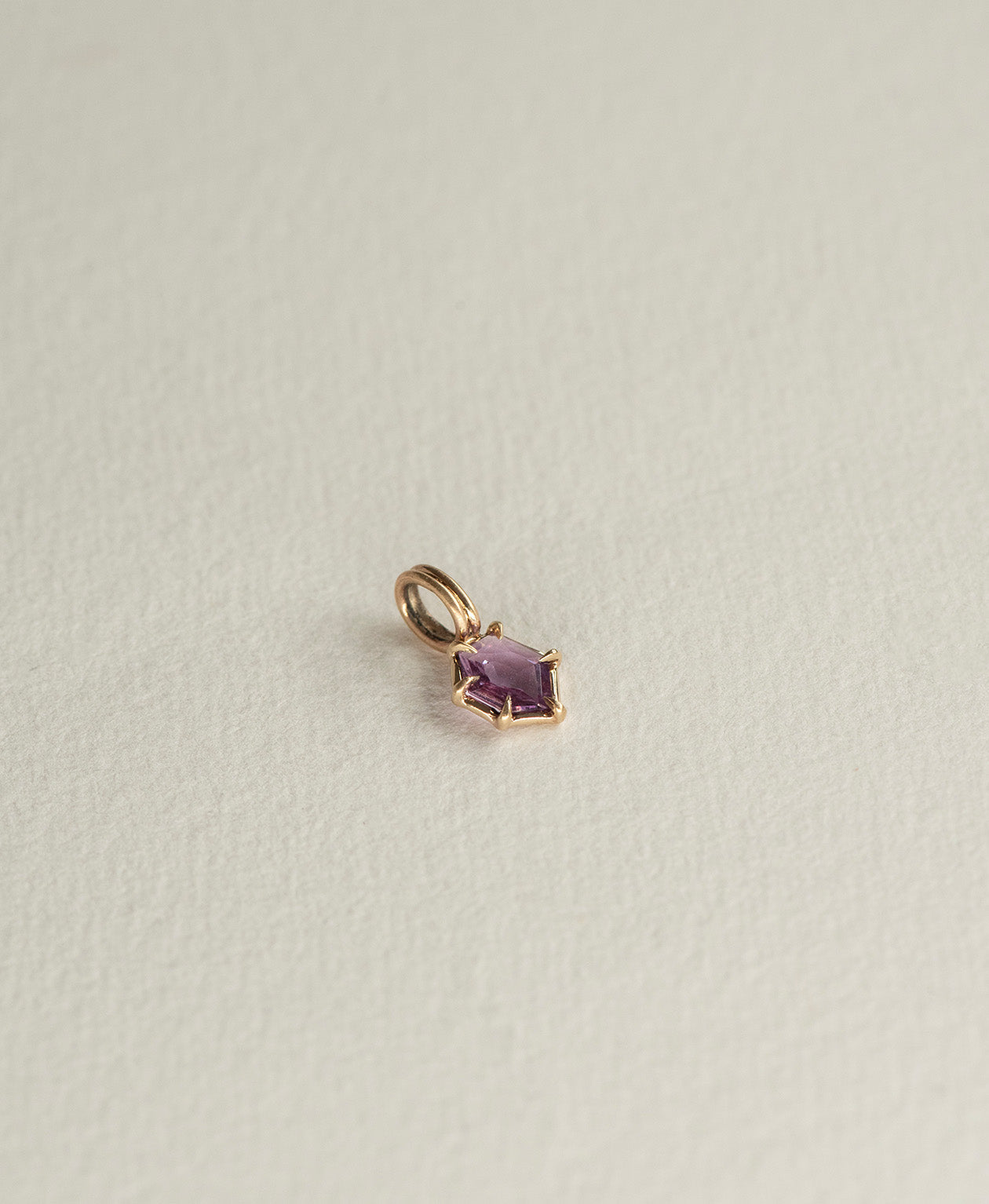 Angled view of the One of a Kind Charm 505 in 9k Yellow Gold with a deep purple hexagonal cut Sapphire.
