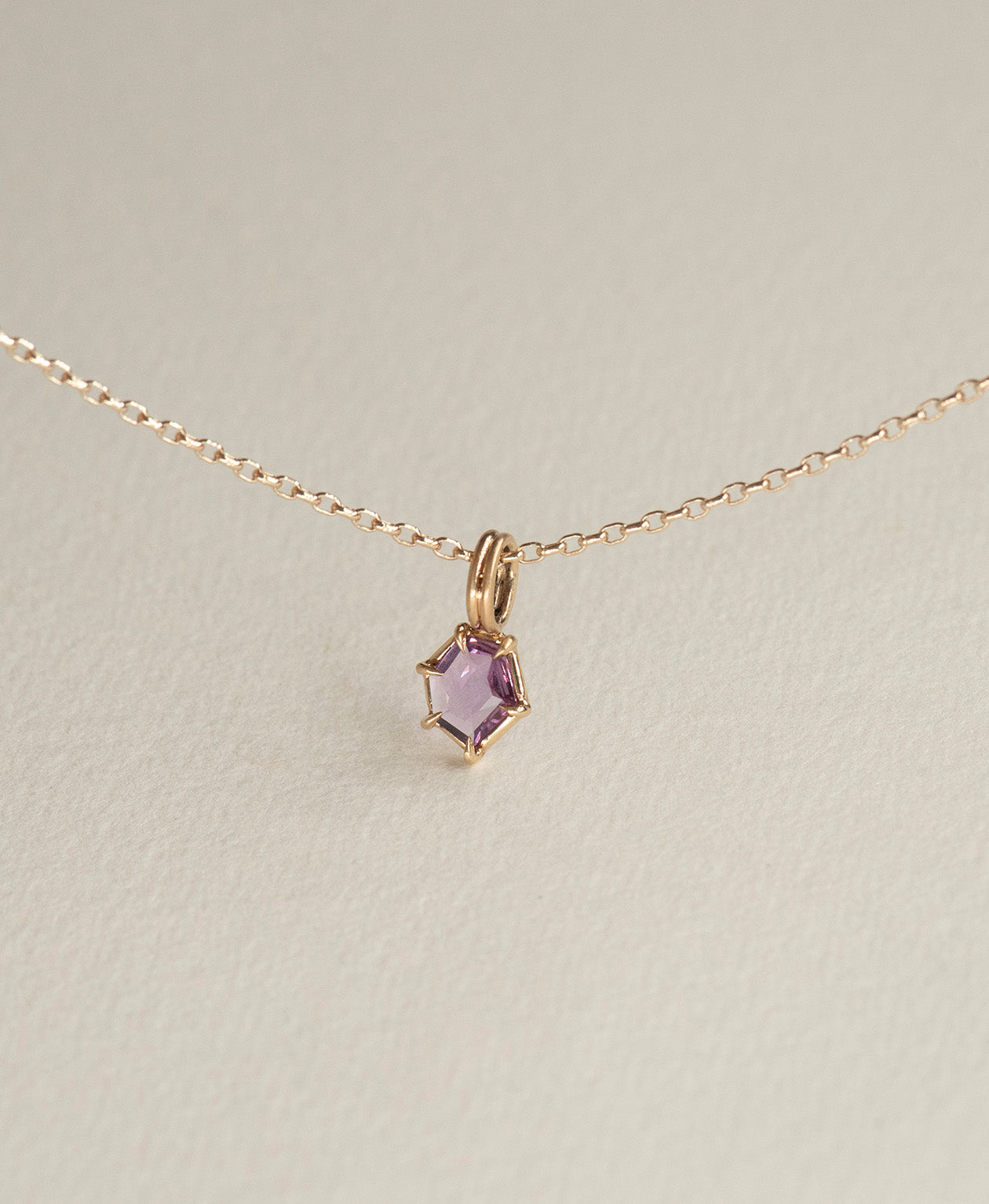 Close up of the One of a Kind Charm 505 with a deep purple hexagonal cut Sapphire on a fine belcher chain.