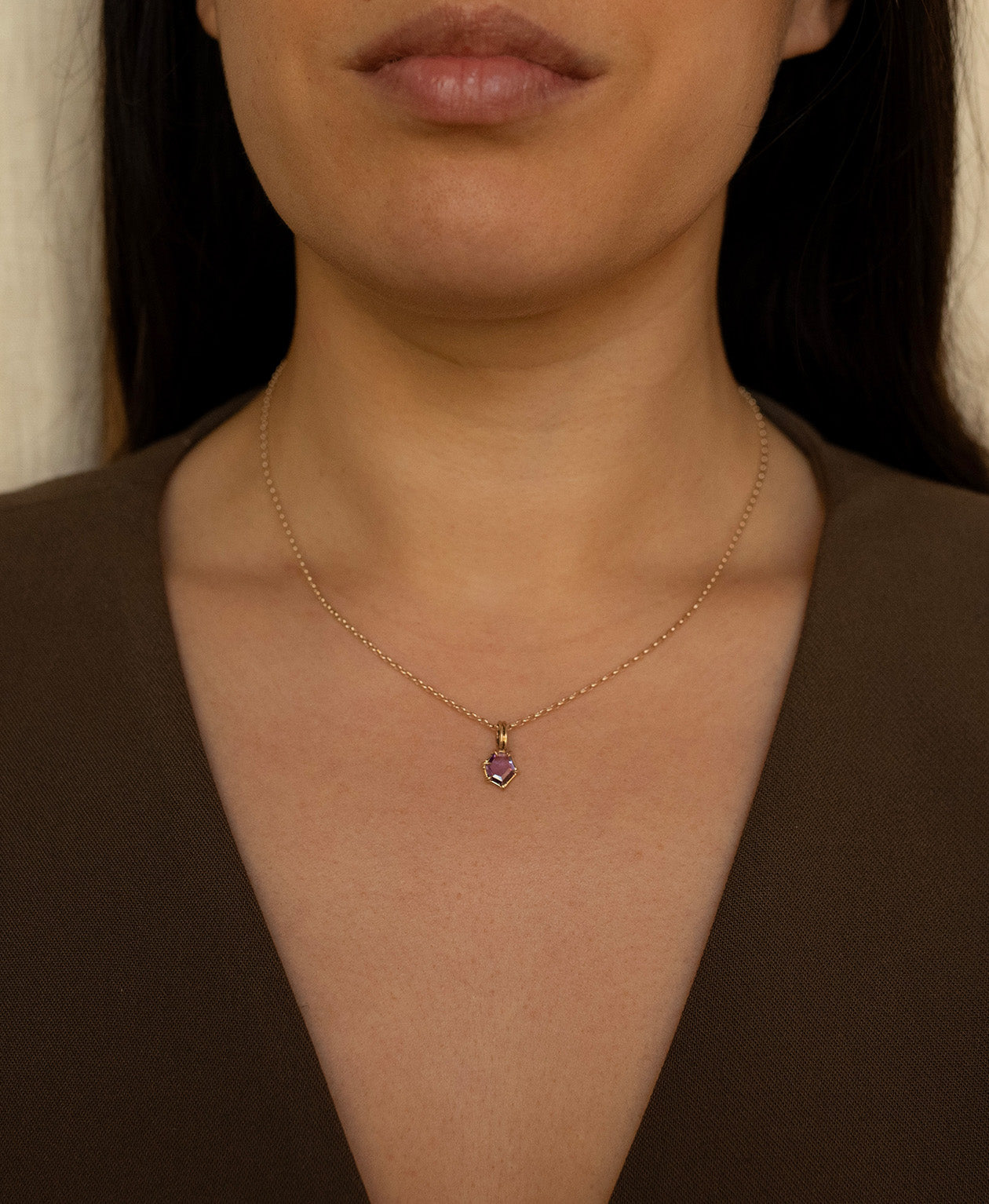 Close up of the One of a Kind Charm 505 with a deep purple hexagonal cut Sapphire worn by a model on a fine belcher chain.