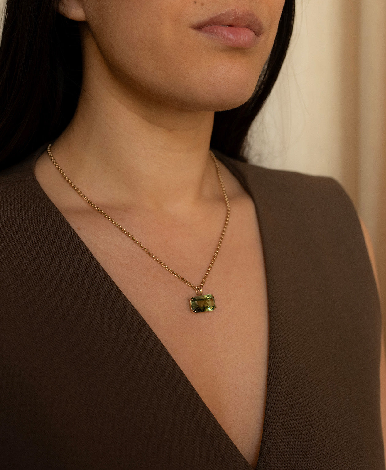 Close up of the One of a Kind Charm 513 with a deep green emerald cut Peridot worn by a model on a belcher chain.