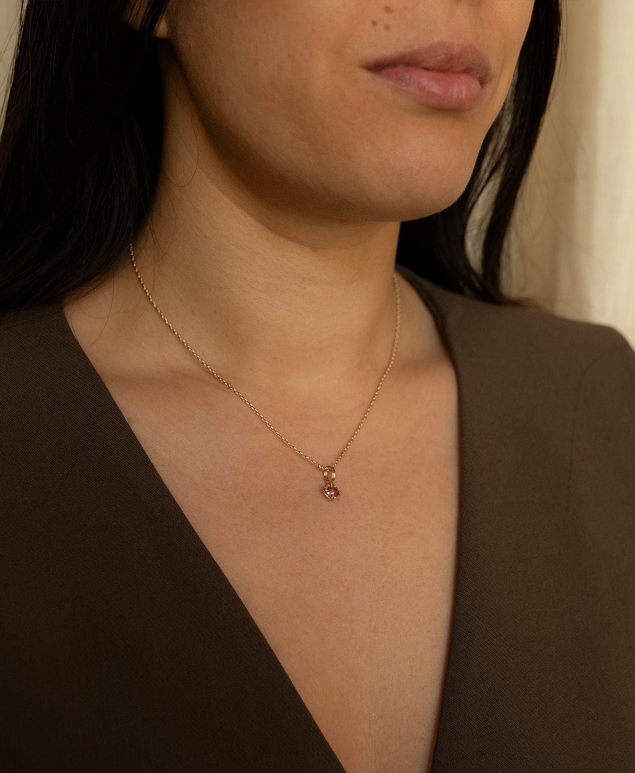 Close up of the One of a Kind Charm 520 with a pink oval cut Garnet worn by a model on a fine belcher chain.