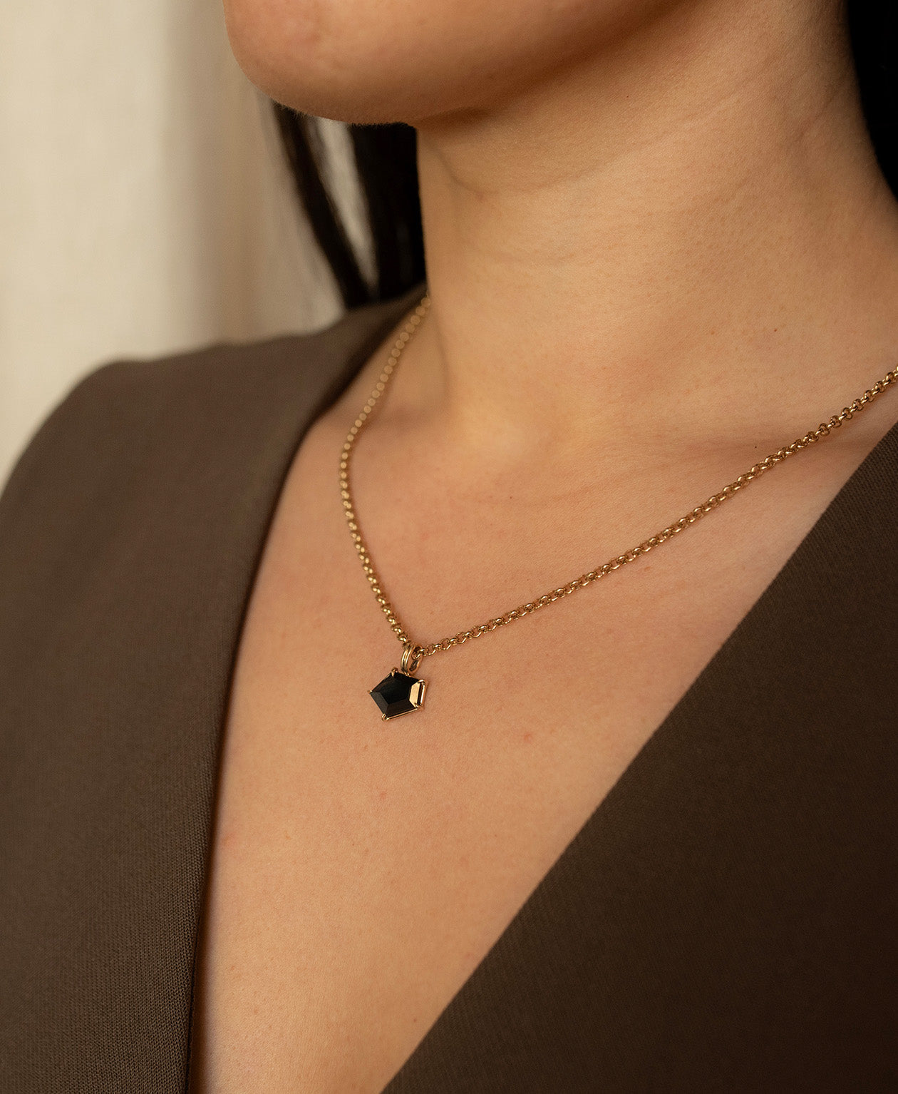 Close up of the One of a Kind Charm 497 with a dark teal portrait cut Sapphire worn by a model on a belcher chain. 
