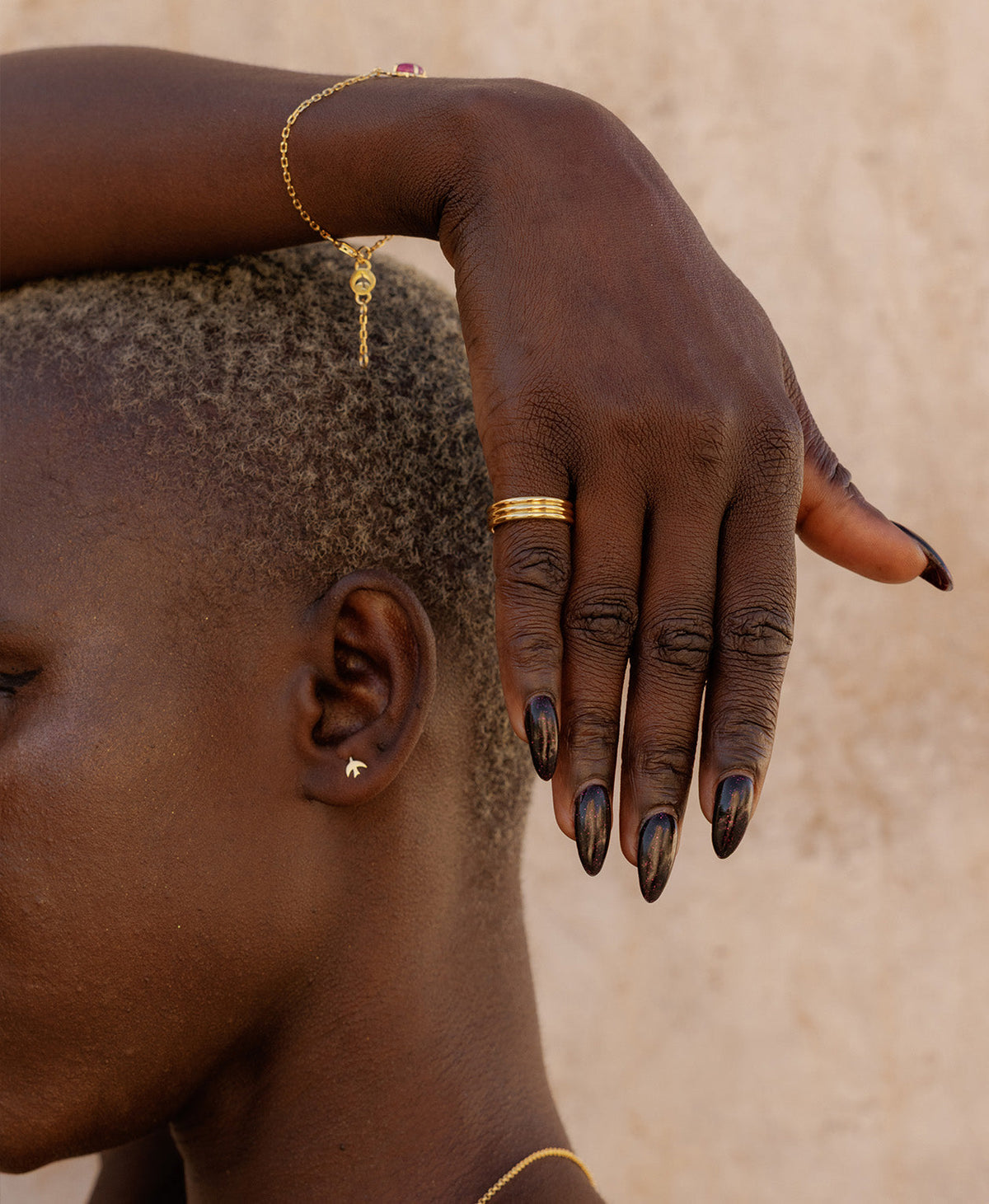 A closeup of a hand wearing the gold Irma Stacker Ring, formed from three connected bands, layered closely.