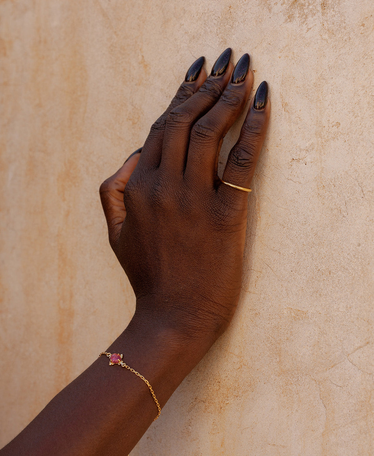 The gold Selma Stacking ring worn on the pinky, paired with a gold bracelet featuring a pink tourmaline. 